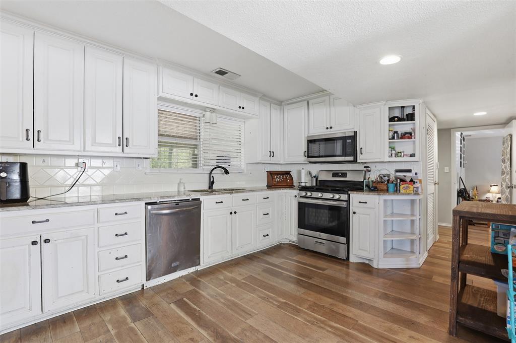 500 West Rucker Street Granbury, TX 76048 - Photo 10 of 35 a kitchen with granite countertop white cabinets and stainless steel appliances