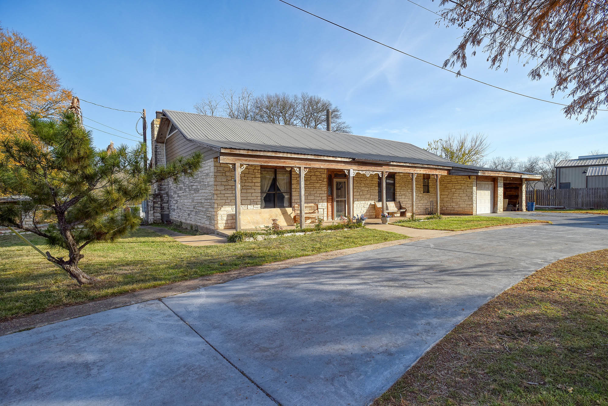 113 My Road Bastrop, TX 78602 - Photo 5 of 35 Ranch-style home with a porch, concrete driveway, a chimney, a front lawn, and a metal roof