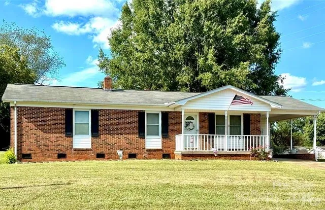 a view of a house with a yard balcony and a large tree