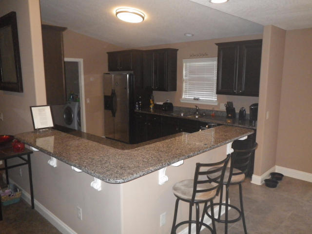 9273 Sundance Court Navarre, FL 32566 - Photo 13 of 33 a kitchen with a sink a refrigerator and chairs