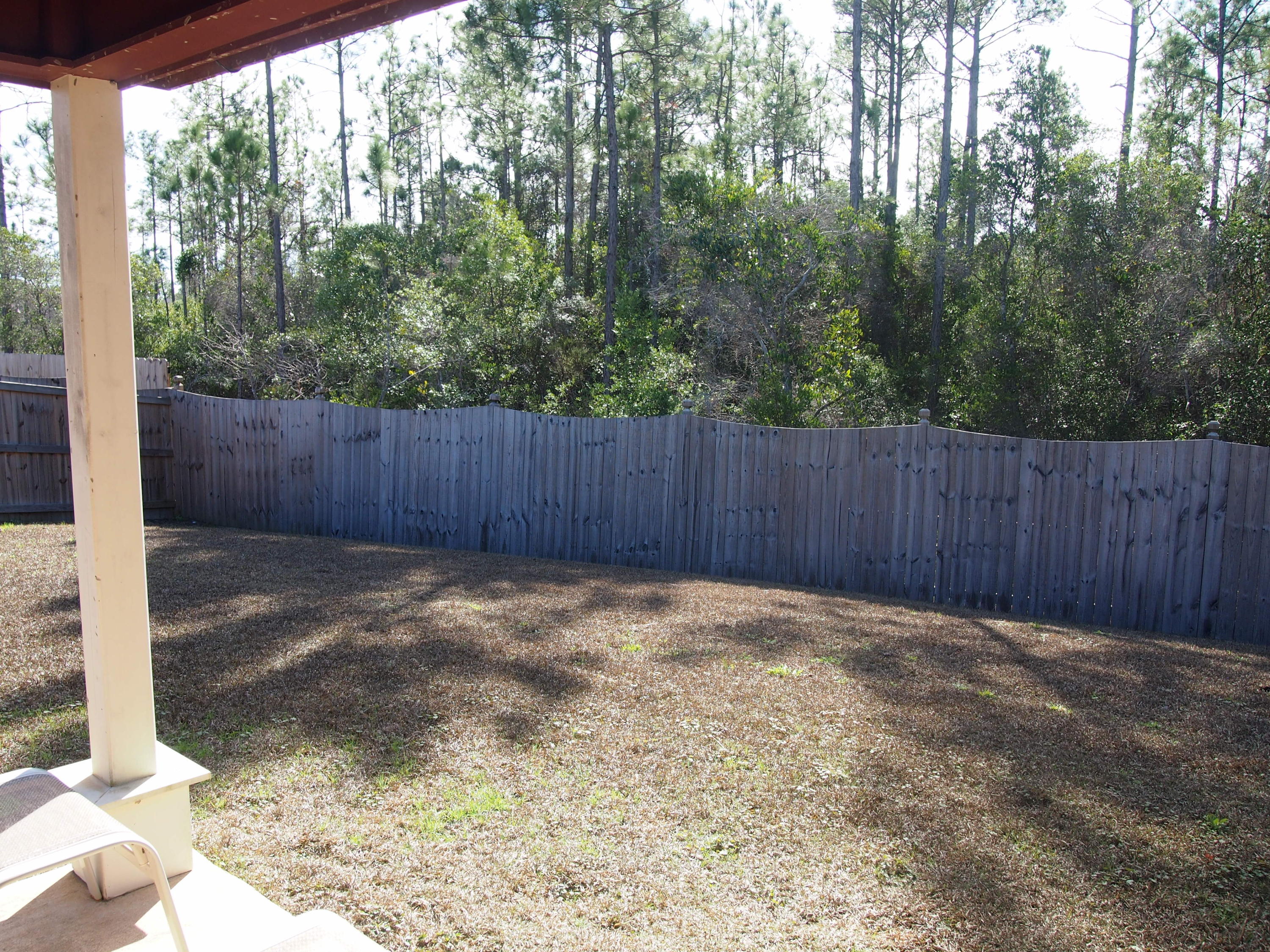 9273 Sundance Court Navarre, FL 32566 - Photo 24 of 33 a view of a backyard with large trees and wooden fence
