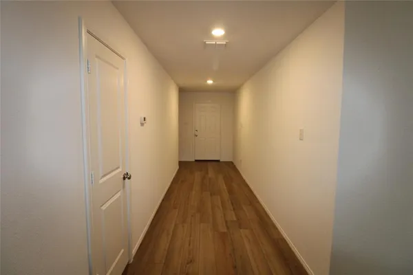 a view of a hallway with wooden floor and a bathroom