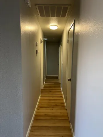 a view of a hallway with wooden floor and staircase