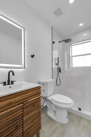 a bathroom with a sink toilet vanity and shower