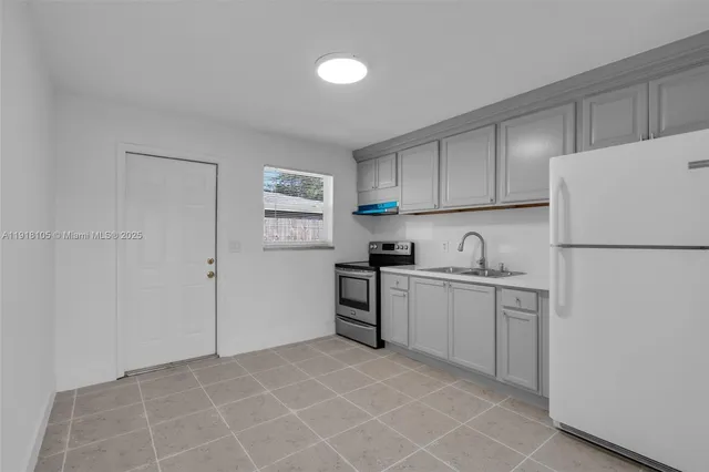 a kitchen with a sink a refrigerator and cabinets