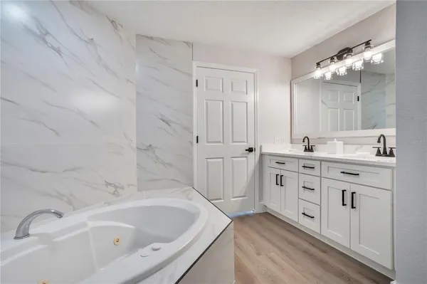 a bathroom with a bathtub sink double vanity and mirror