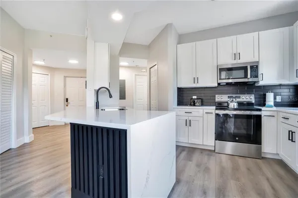a kitchen with stainless steel appliances a sink dishwasher a refrigerator and a stove with wooden floor