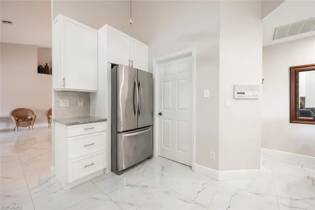 a kitchen with white cabinets and refrigerator
