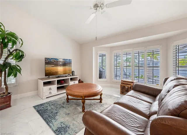 a living room with furniture a flat screen tv and a large window