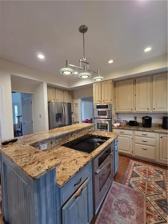 a large kitchen with stainless steel appliances granite countertop a large stove a sink and a refrigerator