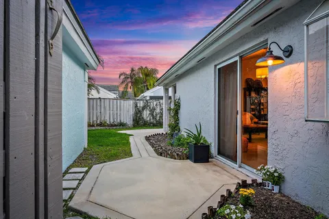 a view of a house with brick walls and flower plants next to a yard