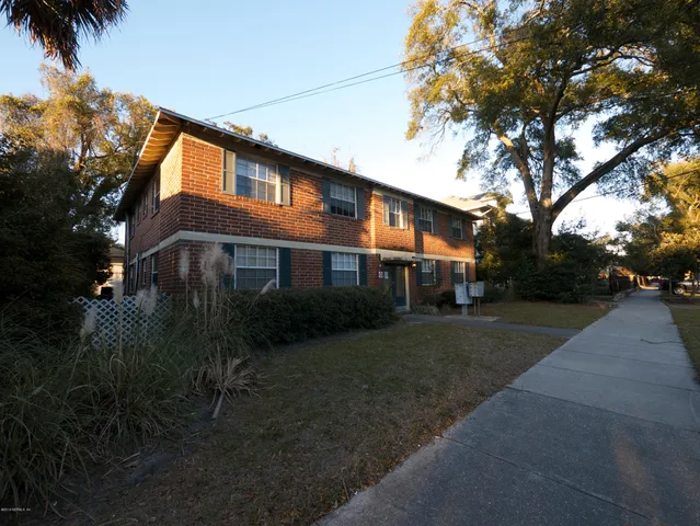 a front view of a house with a garden and trees