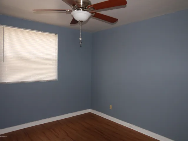 a view of a small space with wooden floor a window and a ceiling fan