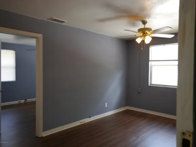 a view of an empty room with wooden floor and a window