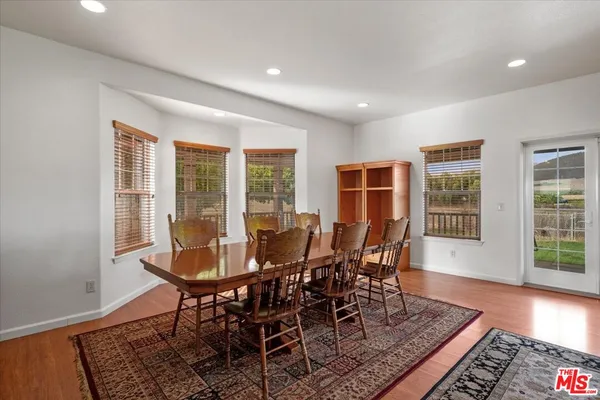 a kitchen with stainless steel appliances granite countertop a refrigerator a sink dishwasher a s stove top oven a dining table and chairs with wooden floor