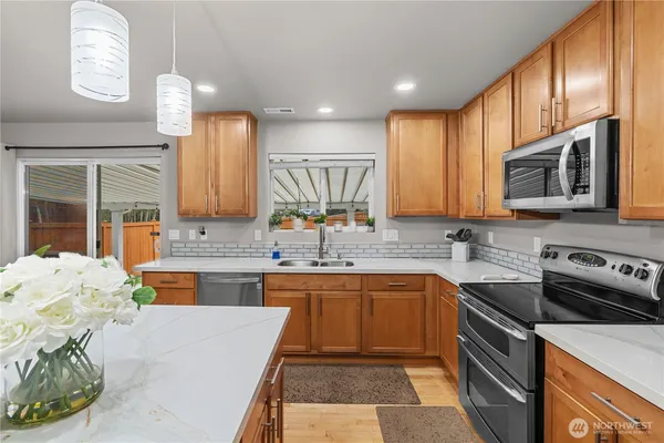 a kitchen with stainless steel appliances granite countertop a sink stove microwave and refrigerator