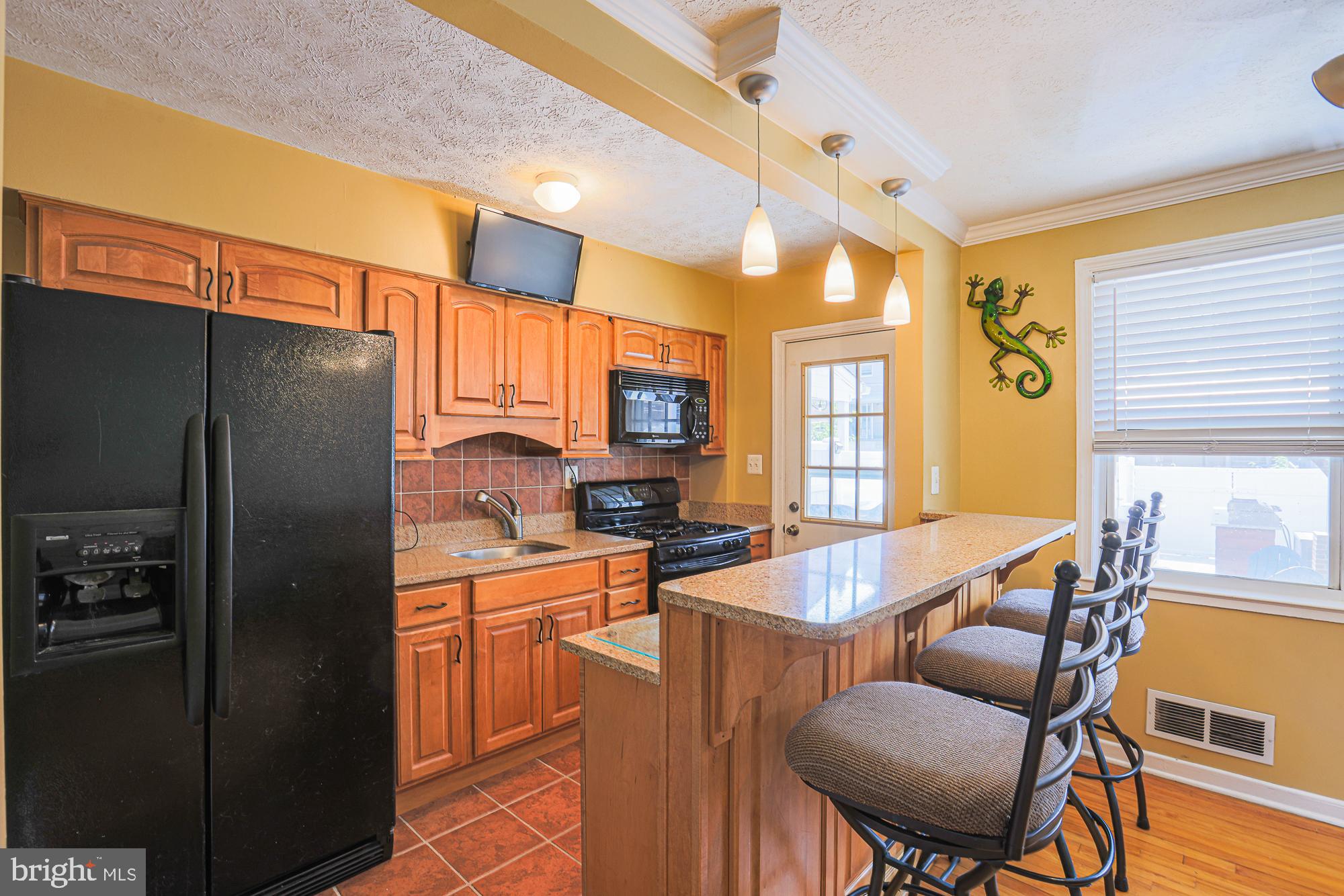 8343 Hillendale Road Baltimore, MD 21234 - Photo 11 of 35 a kitchen with stainless steel appliances granite countertop a refrigerator a stove a sink dishwasher and a dining table with chairs