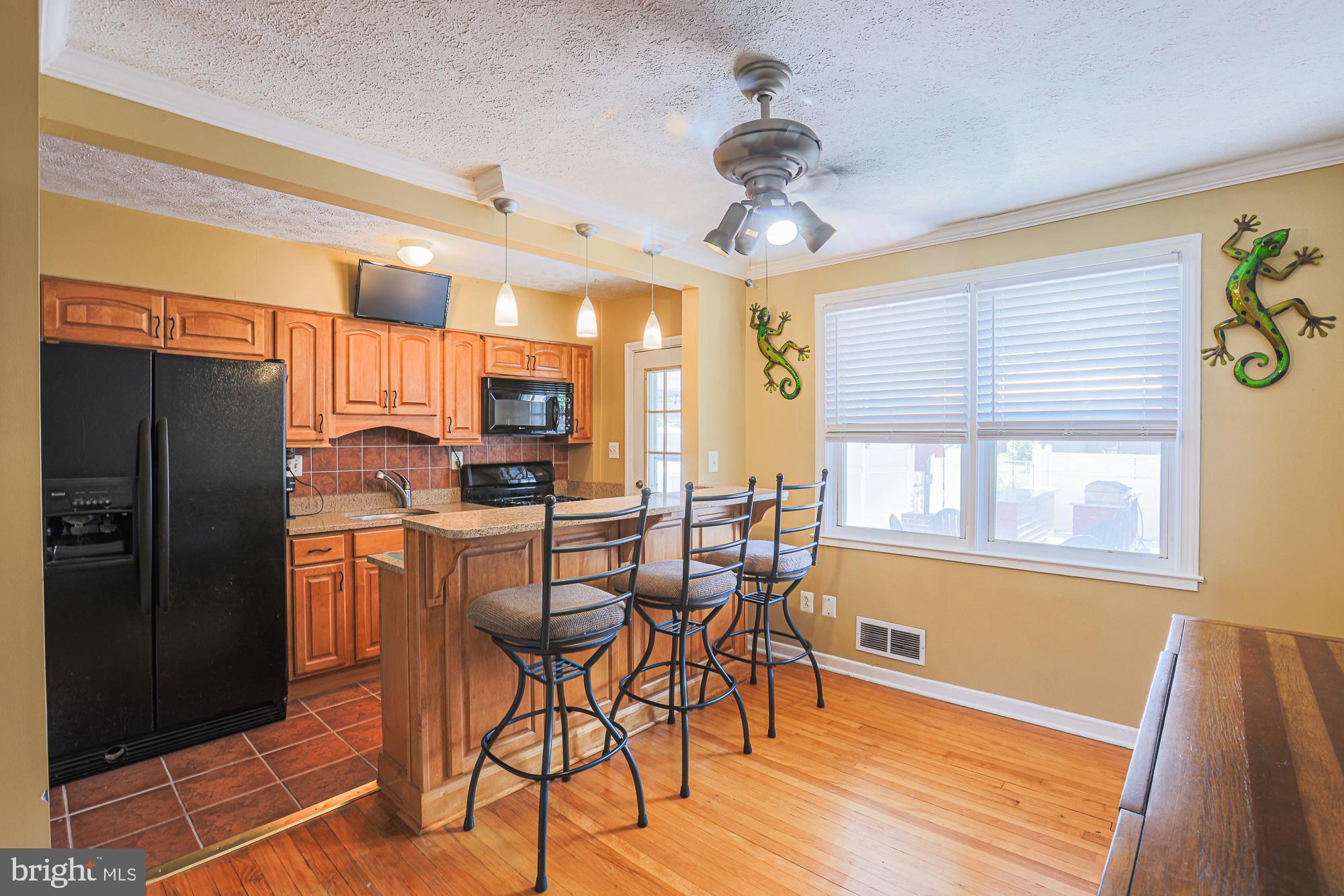 8343 Hillendale Road Baltimore, MD 21234 - Photo 12 of 35 a kitchen with stainless steel appliances kitchen island granite countertop a refrigerator a stove a microwave oven with a dining table and chairs with wooden floor
