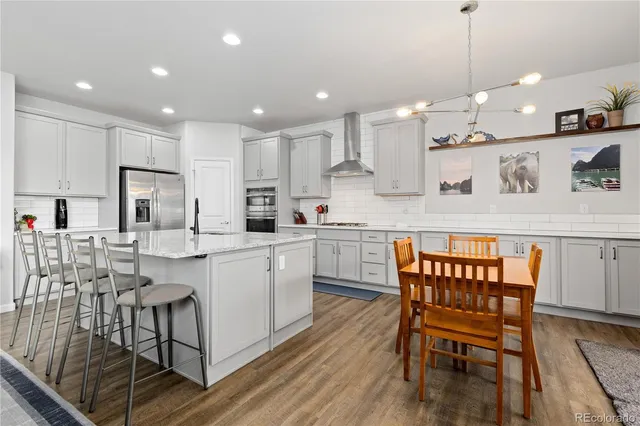 a kitchen with kitchen island granite countertop a table chairs sink and cabinets