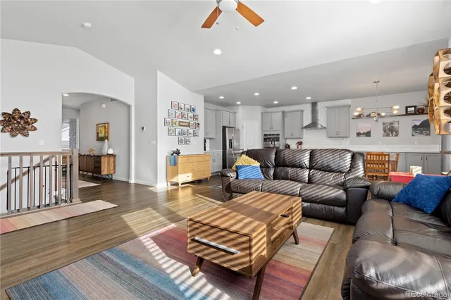 a living room with furniture kitchen view and a wooden floor