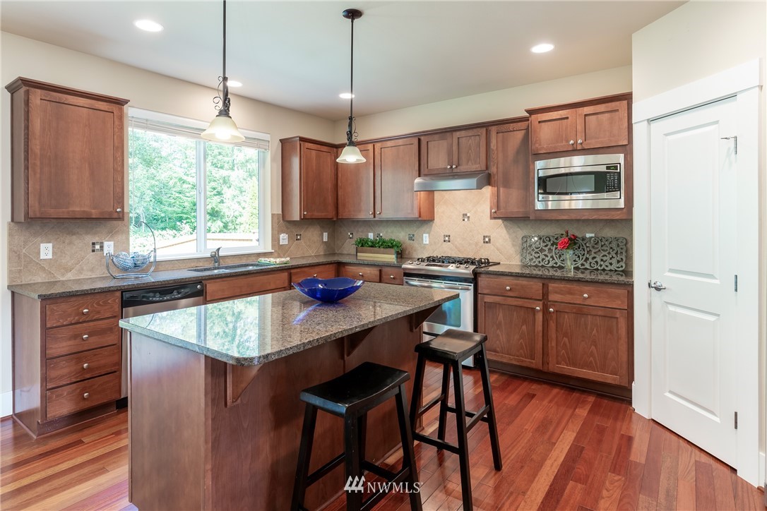 5204 Northeast 9th Place Renton, WA 98059 - Photo 8 of 33 a kitchen with stainless steel appliances granite countertop wooden cabinets a stove a sink dishwasher and a refrigerator with wooden floor