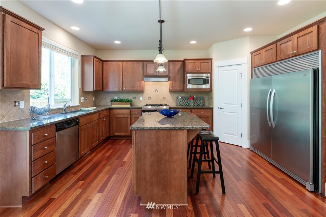 5204 Northeast 9th Place Renton, WA 98059 - Photo 10 of 33 a kitchen with stainless steel appliances granite countertop a refrigerator a sink dishwasher a stove and white countertops with wooden floor