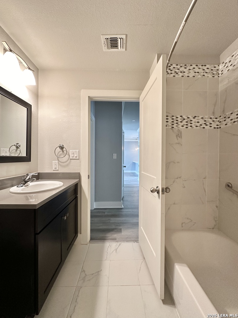 831 Terrell Road, Unit 103 San Antonio, TX 78209 - Photo 7 of 8 a bathroom with a granite countertop sink a mirror and a bathtub