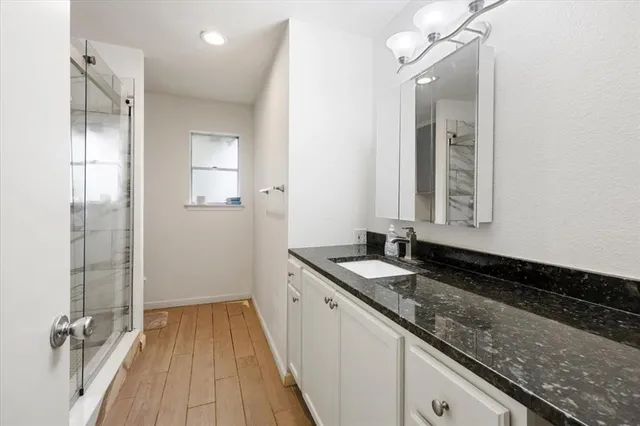 a bathroom with a granite countertop sink a mirror and shower