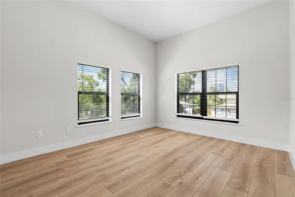 an empty room with wooden floor and windows
