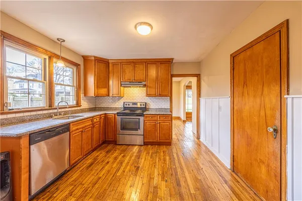a large kitchen with stainless steel appliances granite countertop a refrigerator a sink dishwasher a stove and white countertops with wooden floor