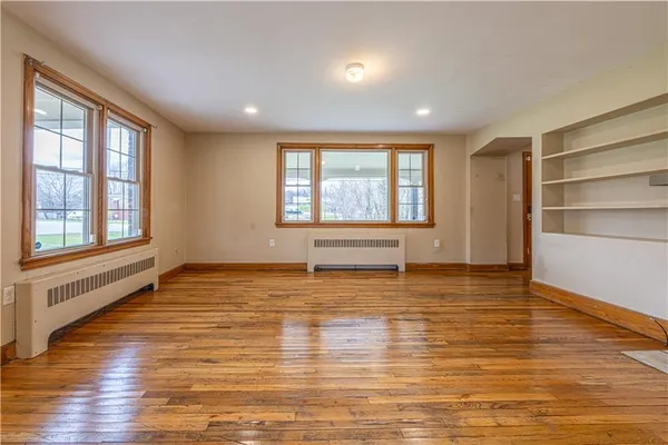 a view of an empty room with window and wooden floor