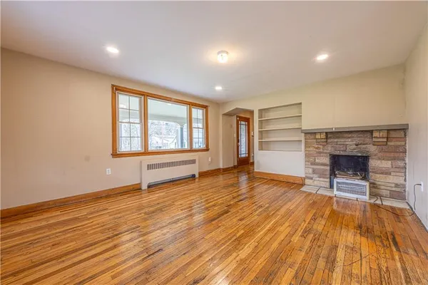 a view of empty room with wooden floor and fireplace