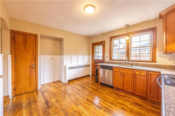 a view of a kitchen with a sink and dishwasher with wooden floor