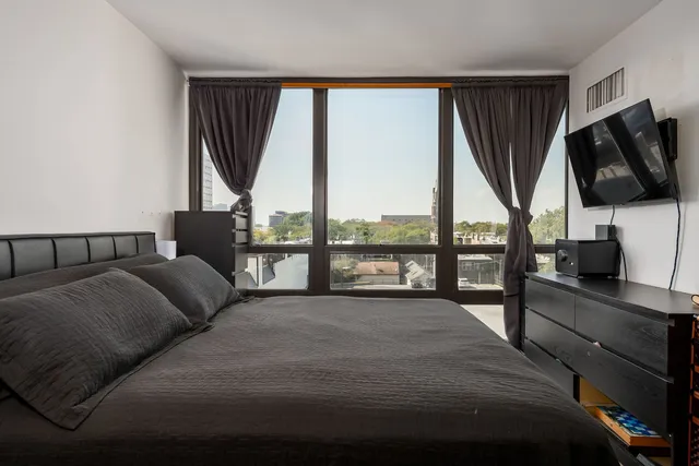 a living room with a bed furniture and a flat tv screen next to a window