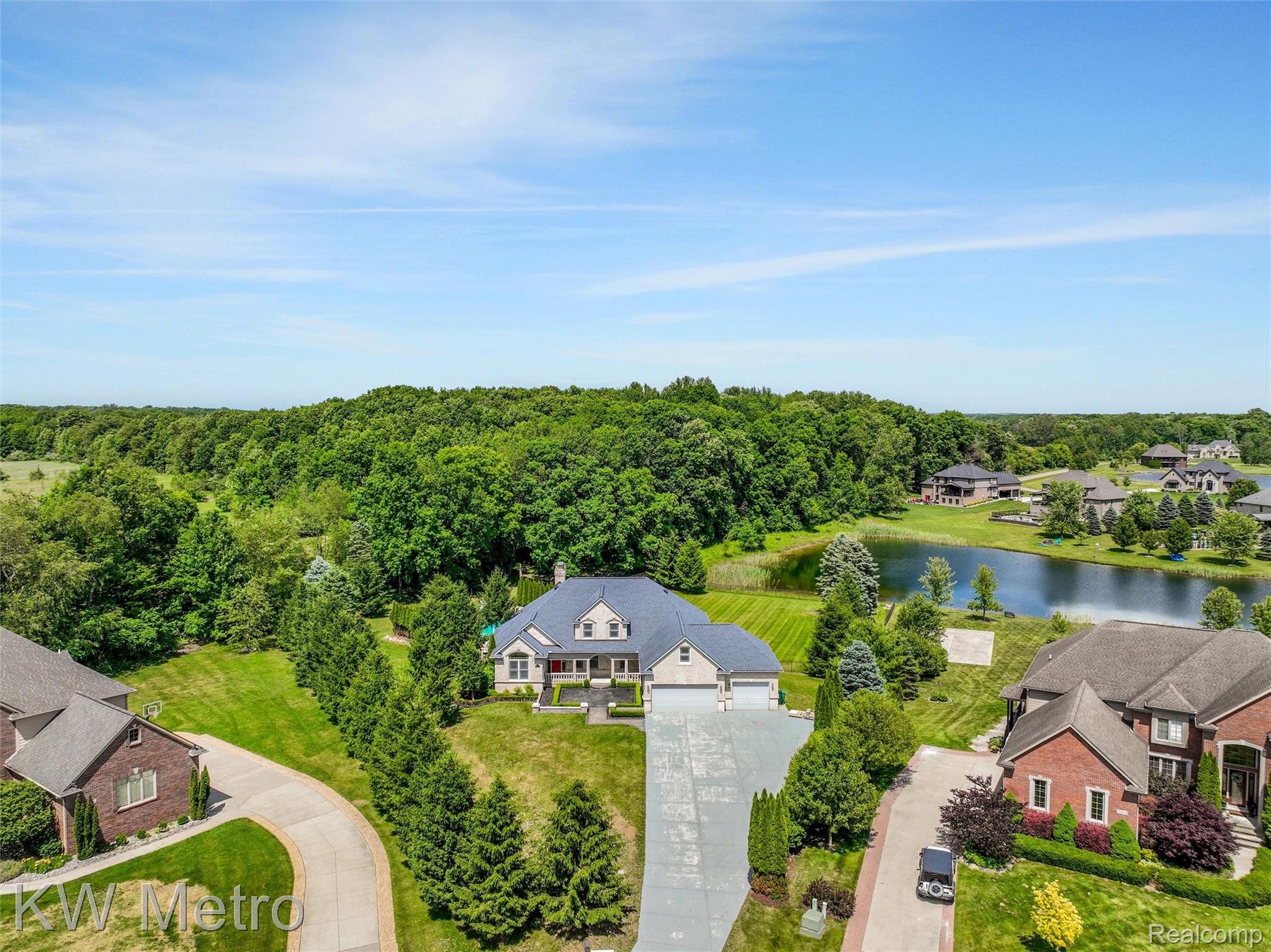 65884 Windrose Court Ray, MI 48096 - Photo 28 of 82 Spacious property featuring a large residence with a light gray facade, multi-car garage, and a lush green lawn