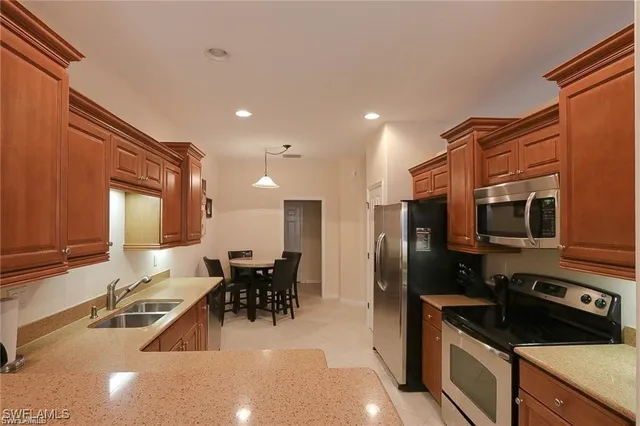 a kitchen with stainless steel appliances a sink a stove a refrigerator cabinets and a dining table