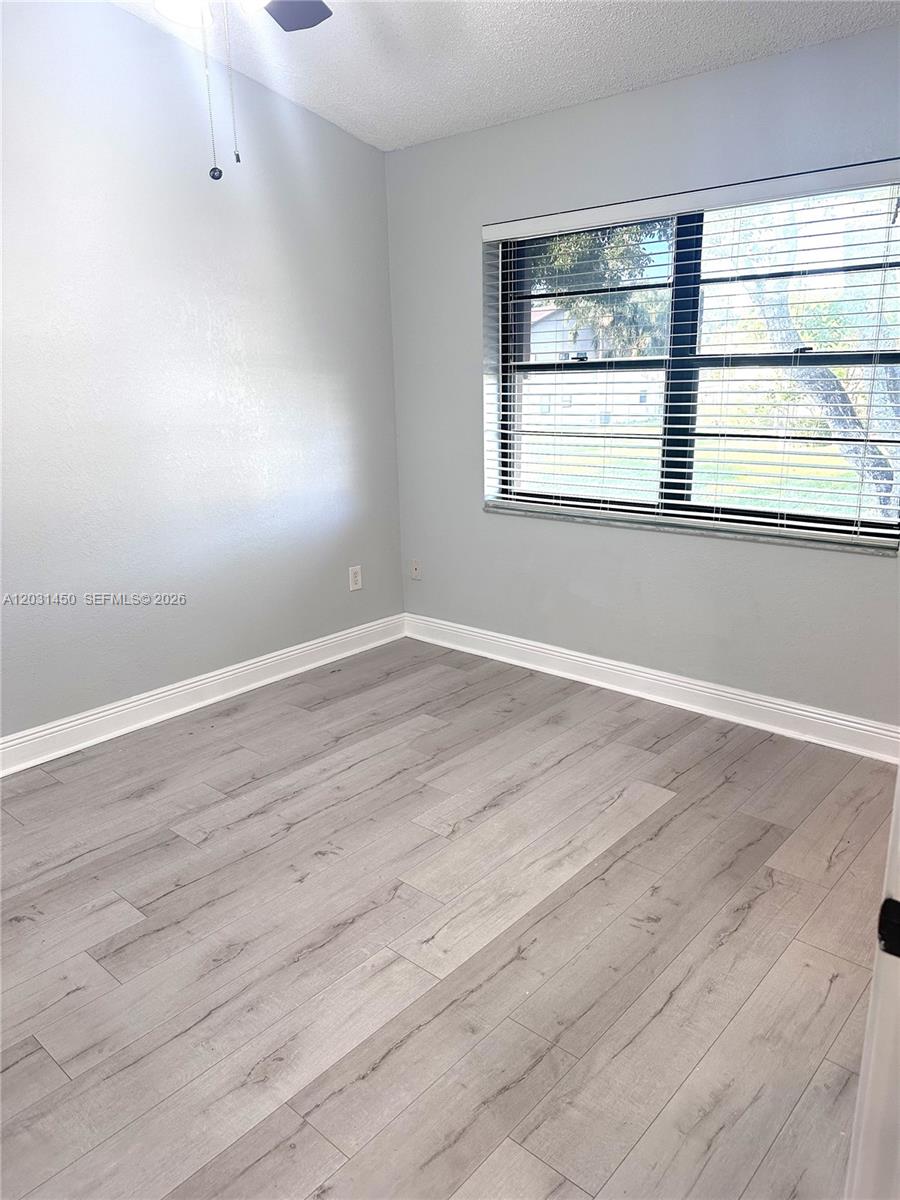 23398 Lyons Road, Unit 309 Boca Raton, FL 33428 - Photo 8 of 16 wooden floor in an empty room with a window