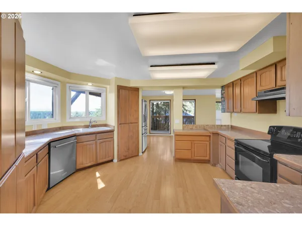 a large kitchen with kitchen island granite countertop a large window and stainless steel appliances