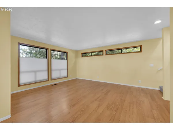 a view of a hallway with wooden floor and windows