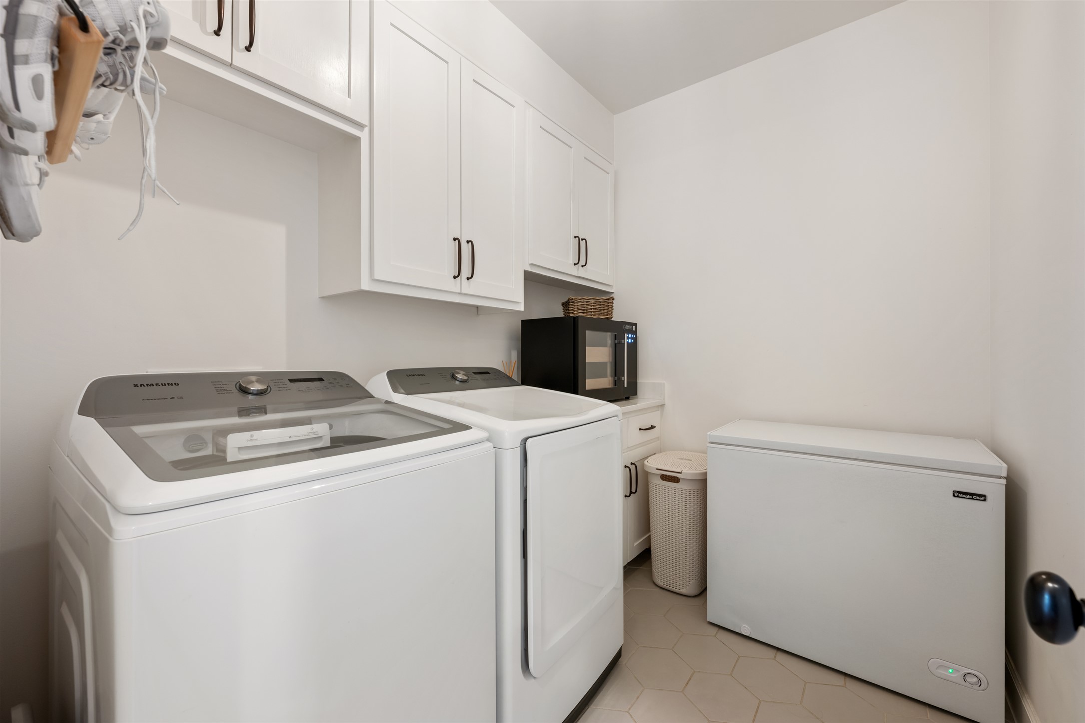 1301 West Street Georgetown, TX 78626 - Photo 29 of 40 Functional laundry room equipped with upper cabinetry, a wine cooler, and hexagon tile flooring.