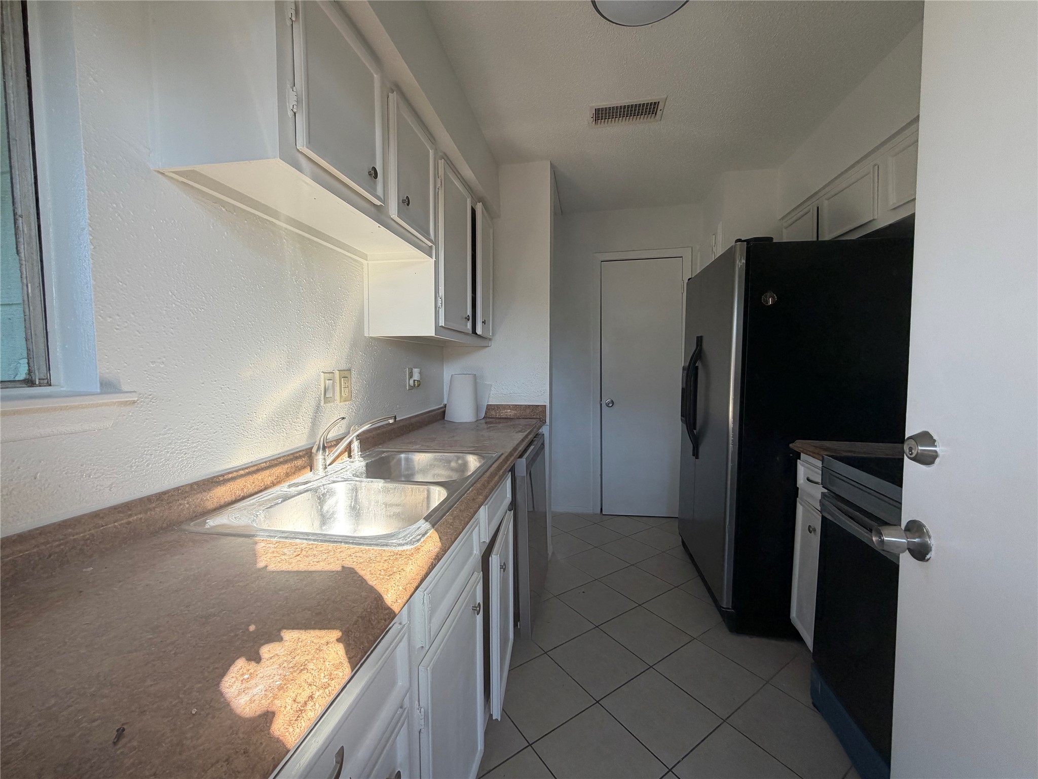7821 Cook Road Houston, TX 77072 - Photo 5 of 14 a kitchen with a refrigerator and a sink