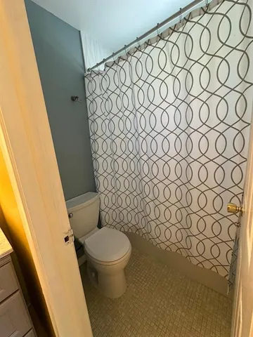 a white toilet sitting next to a shower curtain