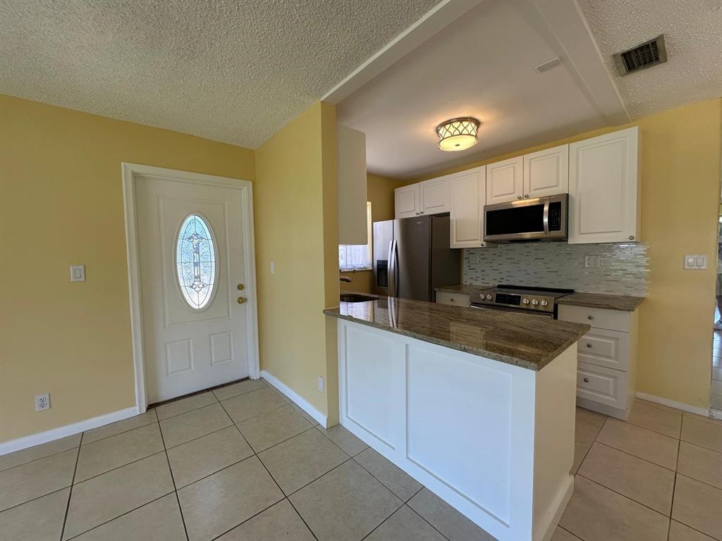 665 High Point Drive Delray Beach, FL 33445 - Photo 3 of 22 a kitchen with granite countertop a stove a sink and a refrigerator