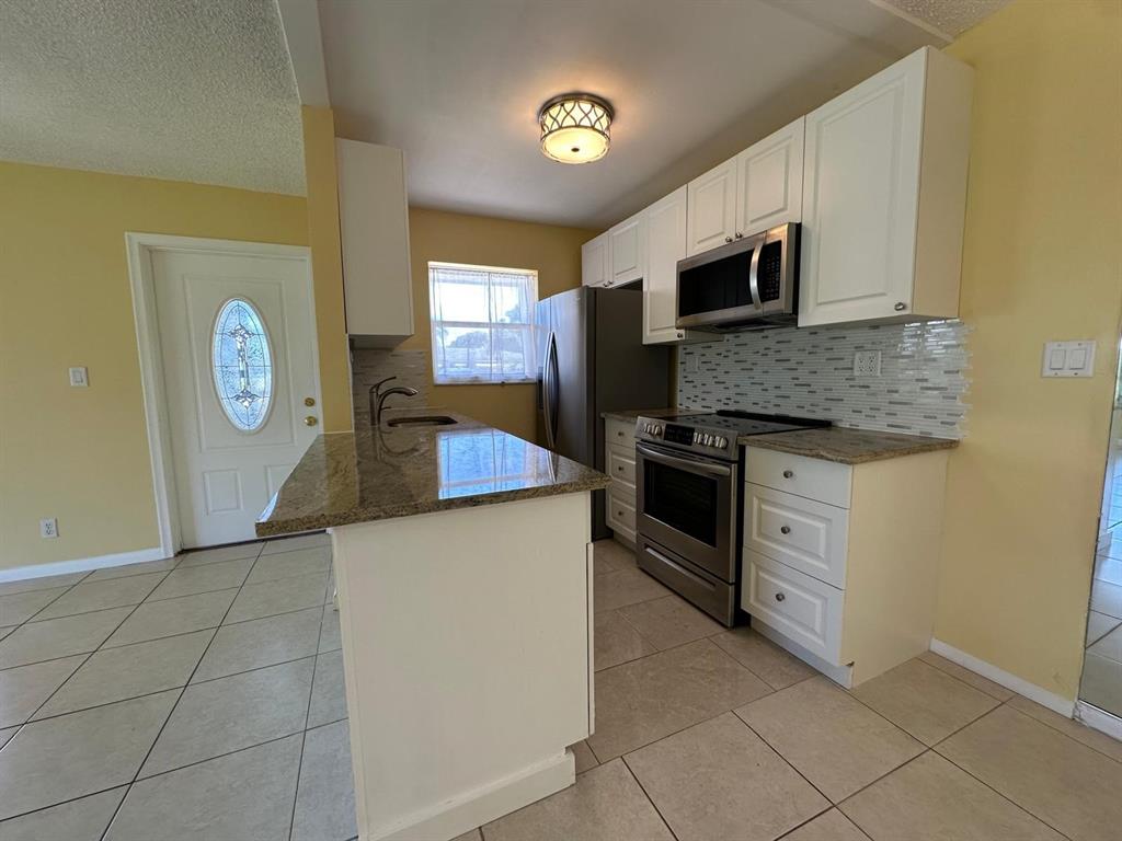 665 High Point Drive Delray Beach, FL 33445 - Photo 5 of 22 a kitchen with stainless steel appliances granite countertop a stove and a sink