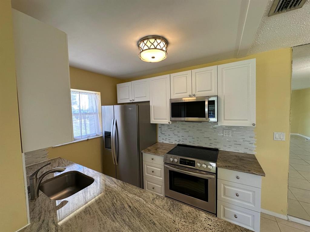 665 High Point Drive Delray Beach, FL 33445 - Photo 7 of 22 a kitchen with stainless steel appliances granite countertop a refrigerator and a stove top oven