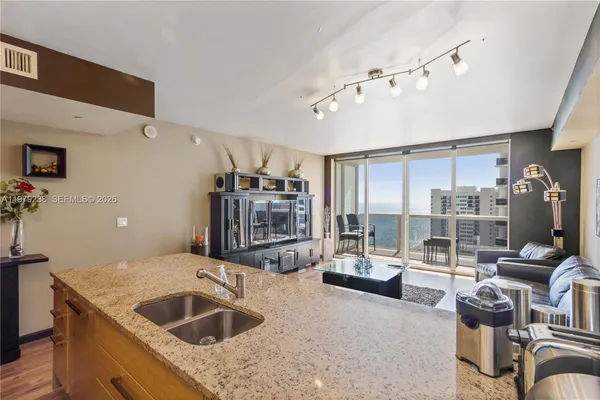 a kitchen with a stove a faucet a chandelier and living room view