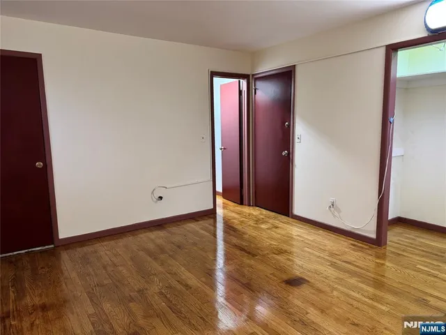 a view of an empty room with wooden floor and closet area