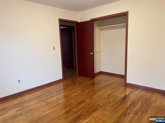 a view of an empty room with wooden floor and closet