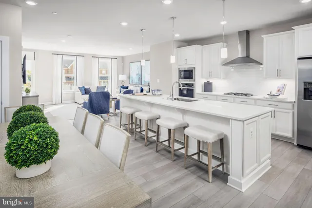 a kitchen with stainless steel appliances kitchen island granite countertop a stove a sink a dining table and chairs