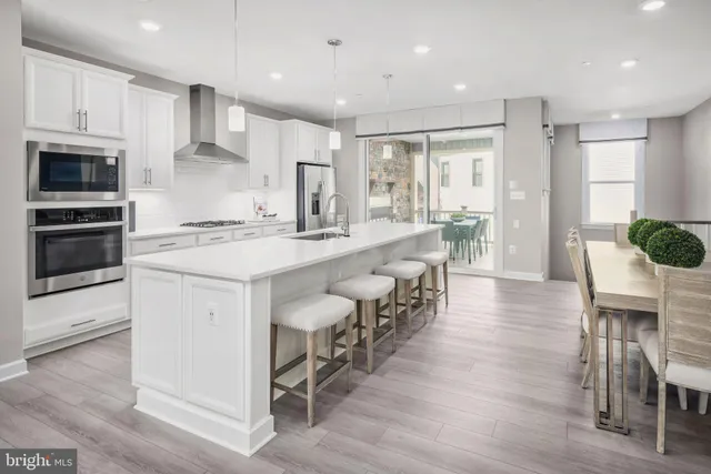 a large kitchen with cabinets chairs and wooden floor